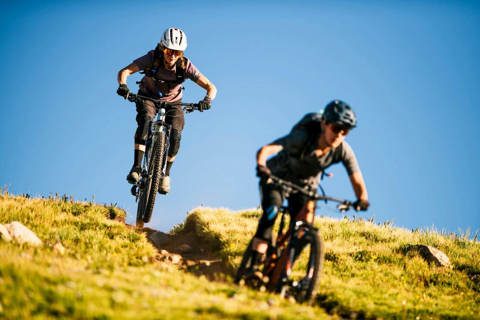 2 mountain bikers riding Juliana mountain bikes down a singletrack trail